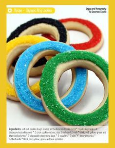 four decorated cookies in the shape of rings on a white table with green, red, yellow and blue frosting