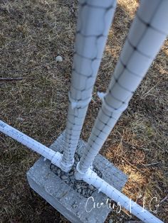 two white pipes sticking out of the ground next to a metal barbwire fence