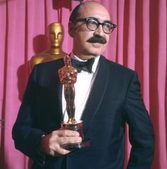 a man in a tuxedo holding an oscar statue