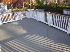 an empty deck with white railings and trees in the background