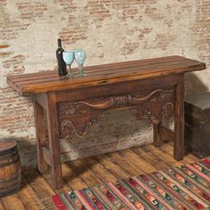 an old wooden table with two wine glasses on it next to a barrel and rug