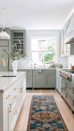 a large rug in the middle of a kitchen with white cabinets and an area rug on the floor