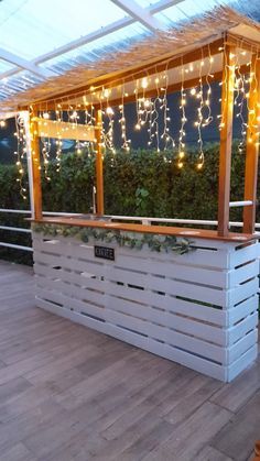 an outdoor bar is decorated with lights and greenery on the roof deck, along with potted plants