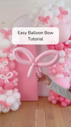 the balloon bow is being held up by a girl in front of pink and white balloons