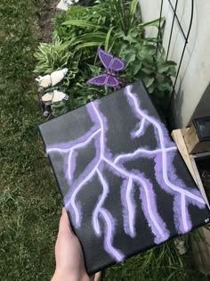 someone is holding up a piece of chalk art in front of some plants and flowers