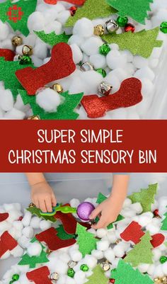 a child is playing with snow and christmas decorations in a bin filled with plastic balls