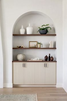 an arch in the wall is filled with shelves and vases