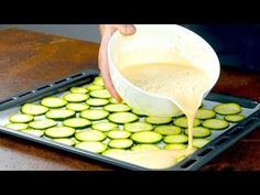 a person pours sauce over sliced cucumbers on a tray