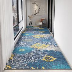 a blue and yellow floral rug is in the hallway next to a large glass window