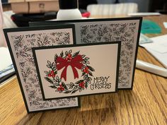 two christmas cards sitting on top of a wooden table