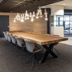 a large wooden table surrounded by chairs and chandeliers in an office setting with wood paneling on the walls