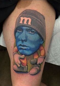 a man's leg with a tattoo on it that has a blue face and an orange hat