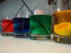 three glasses filled with different colored liquids