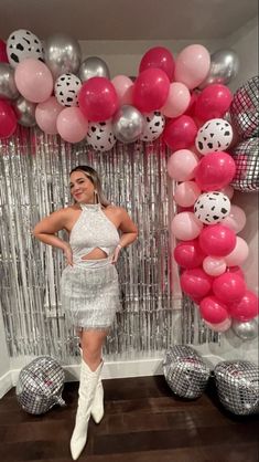 a woman standing in front of balloons and streamers with her hands on her hips