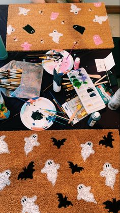 the table is covered with halloween decorations and paintbrushes, paper plates, and other crafting supplies