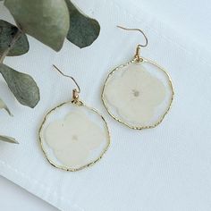 "This listing is for a medium sized pair of White Hydrangea Flower earrings with gold or sliver rims. These earrings are light weight, hand poured, carefully crafted and uniquely designed!  They are created in small batches with real dried flowers, glitter, and premium quality resin. - All of our earrings use NICKEL FREE AND LEAD FREE HYPOALLERGENIC HOOKS, and are the perfect gift for a friend, girlfriend, wife, fiancée or even for yourself!  Every earring is hand crafted and so each are unique! VARIATIONS -You can find these White Hydrangea earrings with a gold or silver rim in the variations menu HOW TO ORDER: 1.  Select the quantity that you would like to purchase 2. Choose your shipping method 3.  Enter your credit card information and PLEASE DOUBLE CHECK THAT YOUR DELIVERY ADDRESS IS White Pressed Flower Earrings For Wedding, White Flower Earrings With Pressed Flowers For Wedding, Elegant White Earrings With Pressed Flowers, Delicate White Earrings With Pressed Flowers, White Birth Flower Earrings In Nature-inspired Style, White Birth Flower Earrings, Nature-inspired, Birth Flower Drop Earrings For Wedding, White Nature-inspired Earrings With Birth Flower, White Birth Flower Nature-inspired Earrings