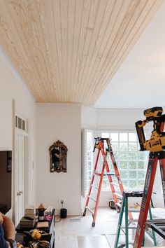 two ladders are in the middle of a room with construction materials on the floor