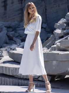 a woman in a white dress standing on rocks