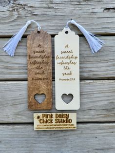 two wooden bookmarks with white tassels on top of each one and a pink dash card attached to the back