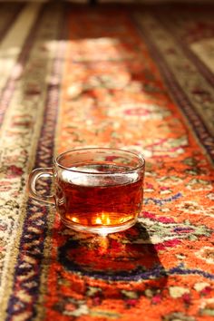 a glass cup filled with tea sitting on top of a rug