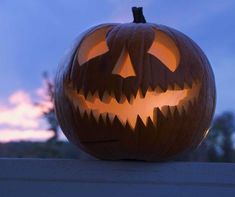 a carved pumpkin sitting on top of a wooden fence