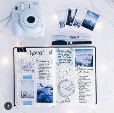 an open travel planner with polaroid camera and other items on the table next to it