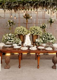 a table topped with lots of white flowers and greenery next to a brick wall