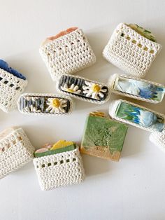 small crocheted purses are arranged on a white surface with flowers in them