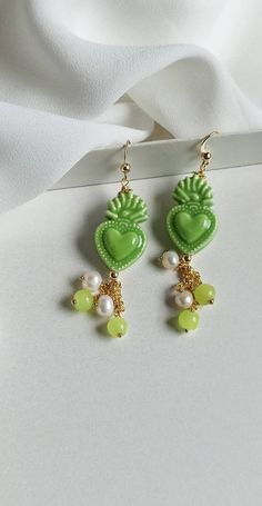 Sicilian earrings made of: - Sicily Ceramic sacred hearts (24 mm x 15 mm), green color; - Smooth stones (4 mm), green color; - Freshwater pearls (4 mm), white color, - 925 open hooks. Lenght : 6 cm / 2,36 inches * SHIPPING * Your order will be shipped within 1-3 business days from your purchase. You can choose between 2 shipping methods: STANDARD MAIL (NOT TRACEABLE) It is a cheap and fast shipping method, but NOT TRACEABLE. Chapeau Atelier is not responsible for any postal disruptions, delays o Green Heart Beads Earrings For Gift, Green Earrings With Heart Beads For Gifts, Green Heart Drop Earrings For Gifts, Green Heart-shaped Earrings For Gifts, Handmade Green Heart Earrings As Gift, Handmade Green Heart Earrings For Gift, Green Pearl Drop Earrings As Gift, Heart-shaped Green Jewelry With Matching Earrings, Green Pearl Drop Earrings For Gift