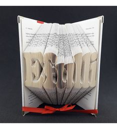 an origami book with the word love folded into it's pages and tied in red ribbon