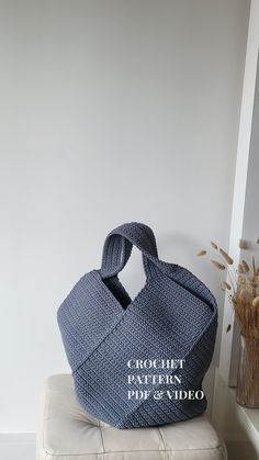 a blue bag sitting on top of a white ottoman next to a vase with dried flowers