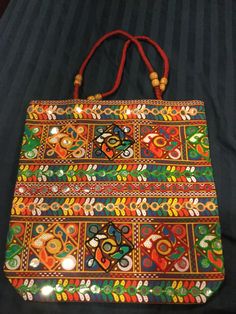 Handmade tote. Very colorful and attractive. Handles have beads. Embroidered with plastic mirrors. Not all mirrors in middle. Plain black on the flip side. Size 15 x 15.5  1 black 2 red 1 green Festive Rectangular Bag With Mirror Work, Handheld Multicolor Bags With Handwork, Festive Multicolor Handheld Bag, Festive Multicolor Handheld Bags, Black Rectangular Shoulder Bag For Festivals, Festive Multicolor Beaded Bag, Multicolor Rectangular Bag With Mirror Work, Rectangular Multicolor Bag With Mirror Work, Embroidered Multicolor Square Shoulder Bag