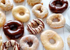 there are many different kinds of donuts on the table and one is white with chocolate drizzles