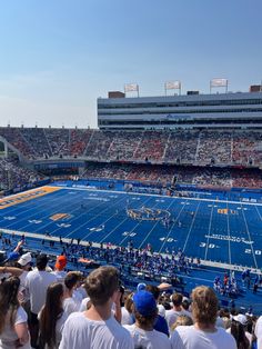 an empty football stadium filled with people watching the game on blue turf and stands full of fans