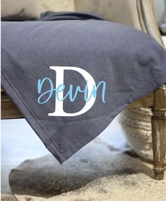 a personalized blanket sitting on top of a chair with the letter d in blue