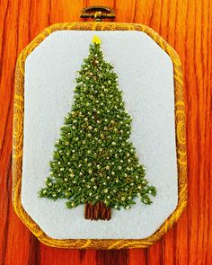 a needled christmas tree in a frame on a wooden table with wood grains