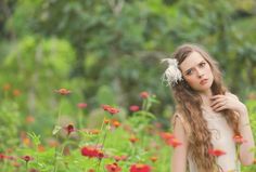 a woman with long hair standing in a field of flowers