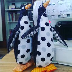 two stuffed penguins sitting next to a sewing machine