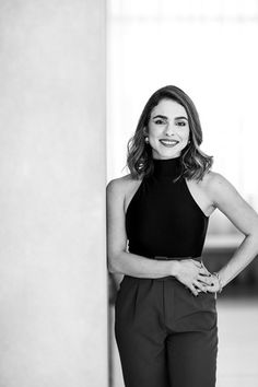 black and white photograph of a woman leaning against a pillar in an office building with her hands on her hips