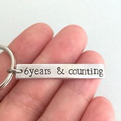 a person holding a keychain with the words years and counting on it's side