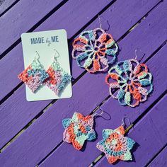 two crocheted flower earrings and a pair of earwires on a purple wooden table