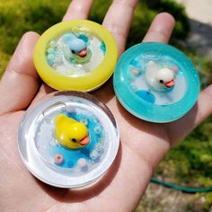 three small rubber ducks floating in water on top of soapy bubbles and plastic discs