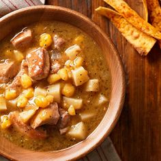 a wooden bowl filled with stew and potatoes