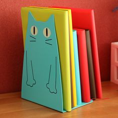 a blue cat bookend sitting on top of a wooden table next to colorful books