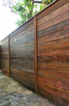 a large wooden fence next to a tree