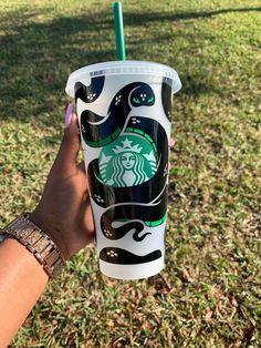 someone holding up a starbucks cup in the grass