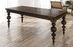 a wooden table sitting on top of a hard wood floor next to a chair and window