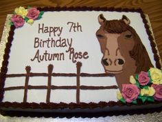 a birthday cake with a horse and flowers on the frosting is sitting on a table