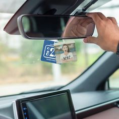 a person is holding up a car id card in the front seat of a vehicle