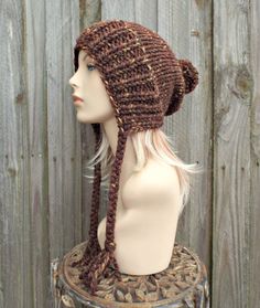 "Style: Chunky knit beanie with pom pom and braided ties, for men or women. Color: This sample hat is shown in Sequoia, a mix of browns, golds and rust. Sizes: One size fits average teen or adult head size of 20\" to 23\" (50.5 cm to 58 cm). Fiber Content: 80% acrylic, 20% Wool Characteristics: Chunky, very soft, warm and cozy. Care Instructions: Hand wash, dry flat. Every item from Pixiebell is handmade and knit or crocheted to order, unless otherwise stated in title of the item as \"ready to s Cozy Brown Crochet Hat In Acrylic Yarn, Chunky Knit Brown Yarn Knitting Pattern, Brown Chunky Knit Yarn Knitting Pattern, Brown Yarn Bonnet Hat, Brown Knitted Yarn Beanie, Knitted Brown Yarn Beanie, Knitted Brown Yarn Bonnet, Brown Hand Knitted Hat In Acrylic Yarn, Hand-knitted Brown Hat In Acrylic Yarn